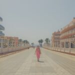 Woman in pink dress walking away down pathway between two hotels