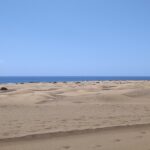 Golden sand dunes with the sea in the distance