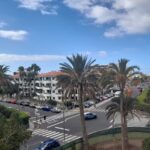 On a Balcony Overlooking Palm Trees, Roads and Buildings with a Blue Sky